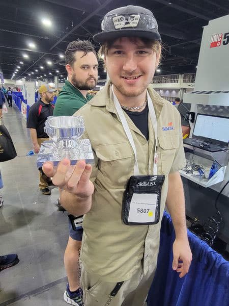 3-MTC-student-Arik-Edstrom-holds-up-his-work-in-CNC-5-Axis-Milling-Programmer-2023-SkillsUSA-competition