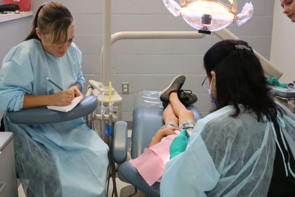 Dental assisting student Jennifer Schmitz takes notes for Dr. Pardo during MTC Project Smart Smiles