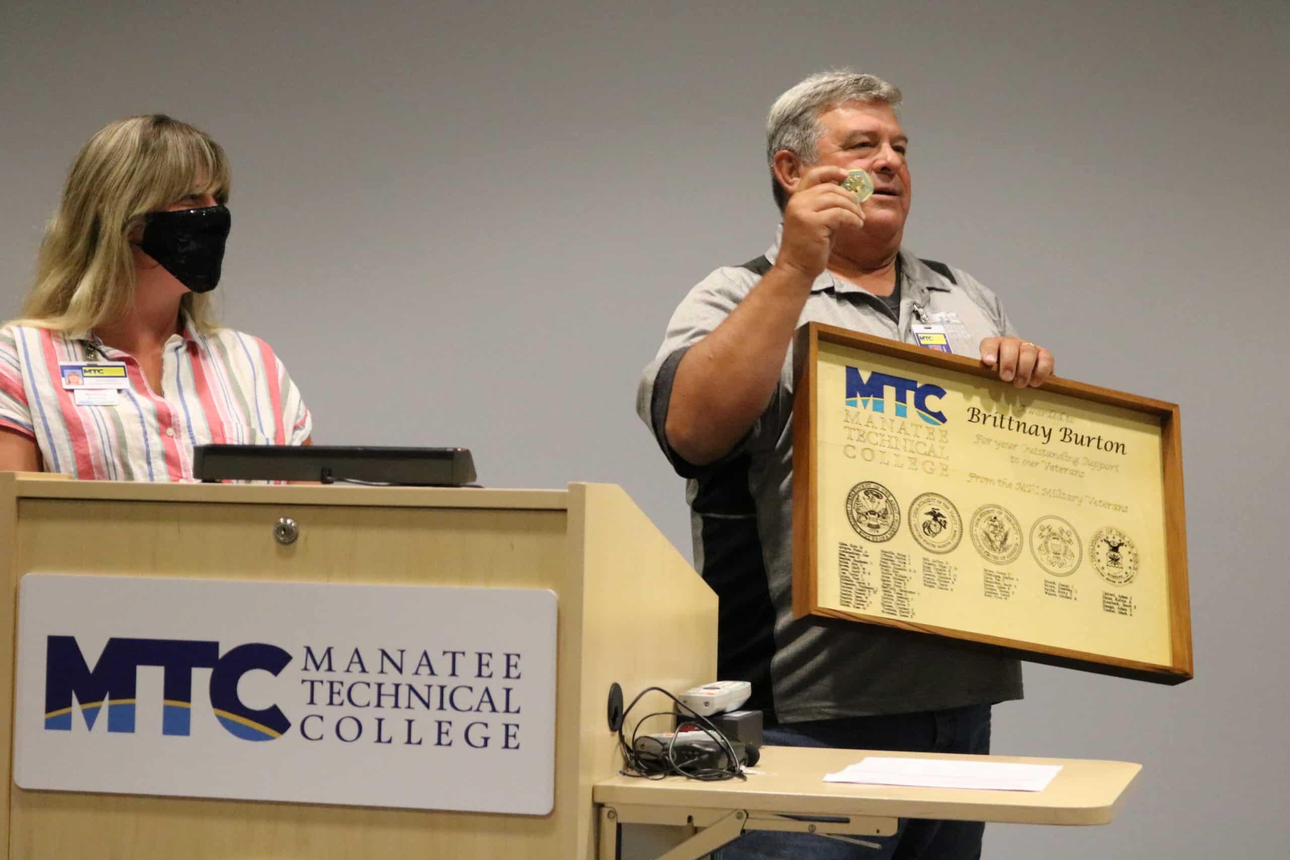 Ret.-Col.-Mike-Ryan-rt-presents-MTC-VA-Benefits-financial-aid-specialist-Brittany-Burton-with-Commanders-coin-a-plaque-he-created-to-thank-her.JPG