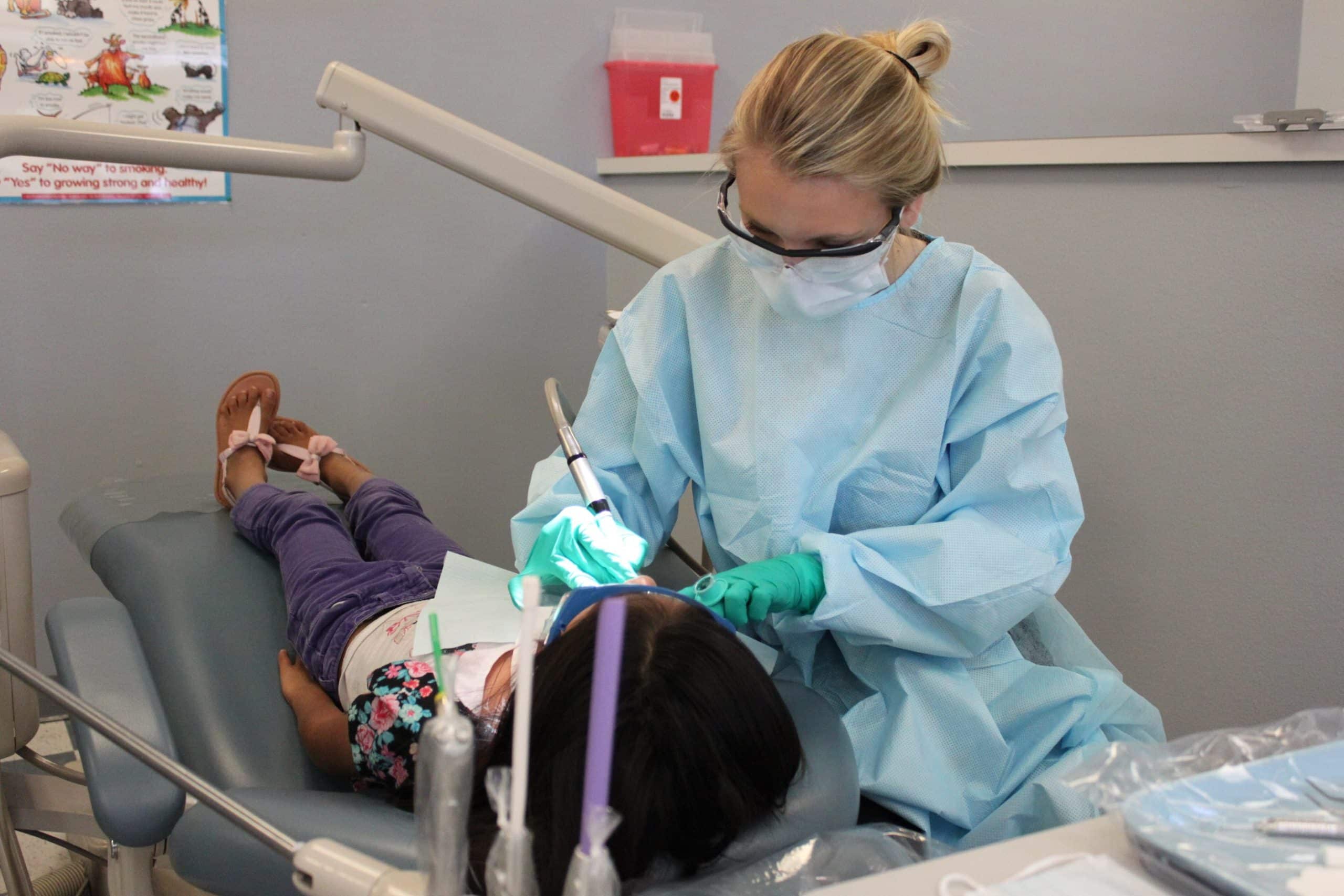 dental assisting student Julia Zevallos polishes teeth of a young patient